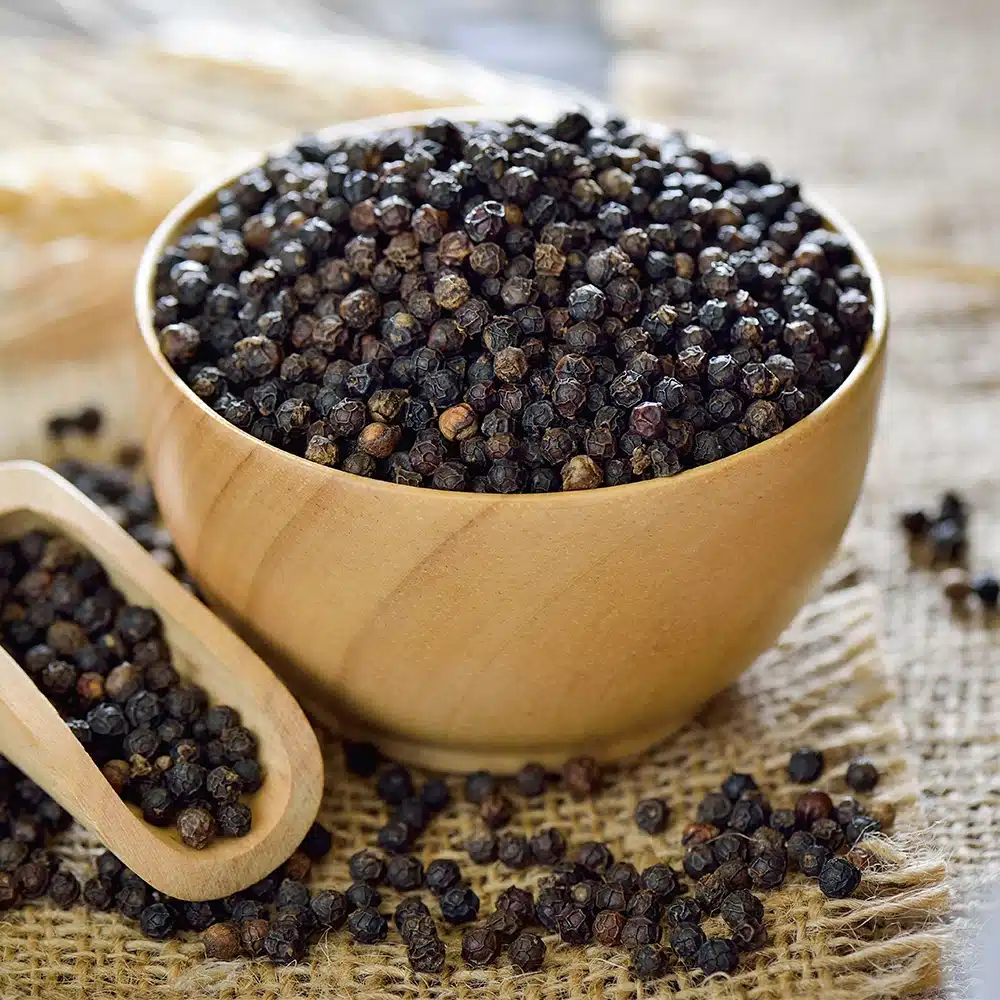 A wooden bowl filled with black pepper, highlighting agricultural and commodity supply.