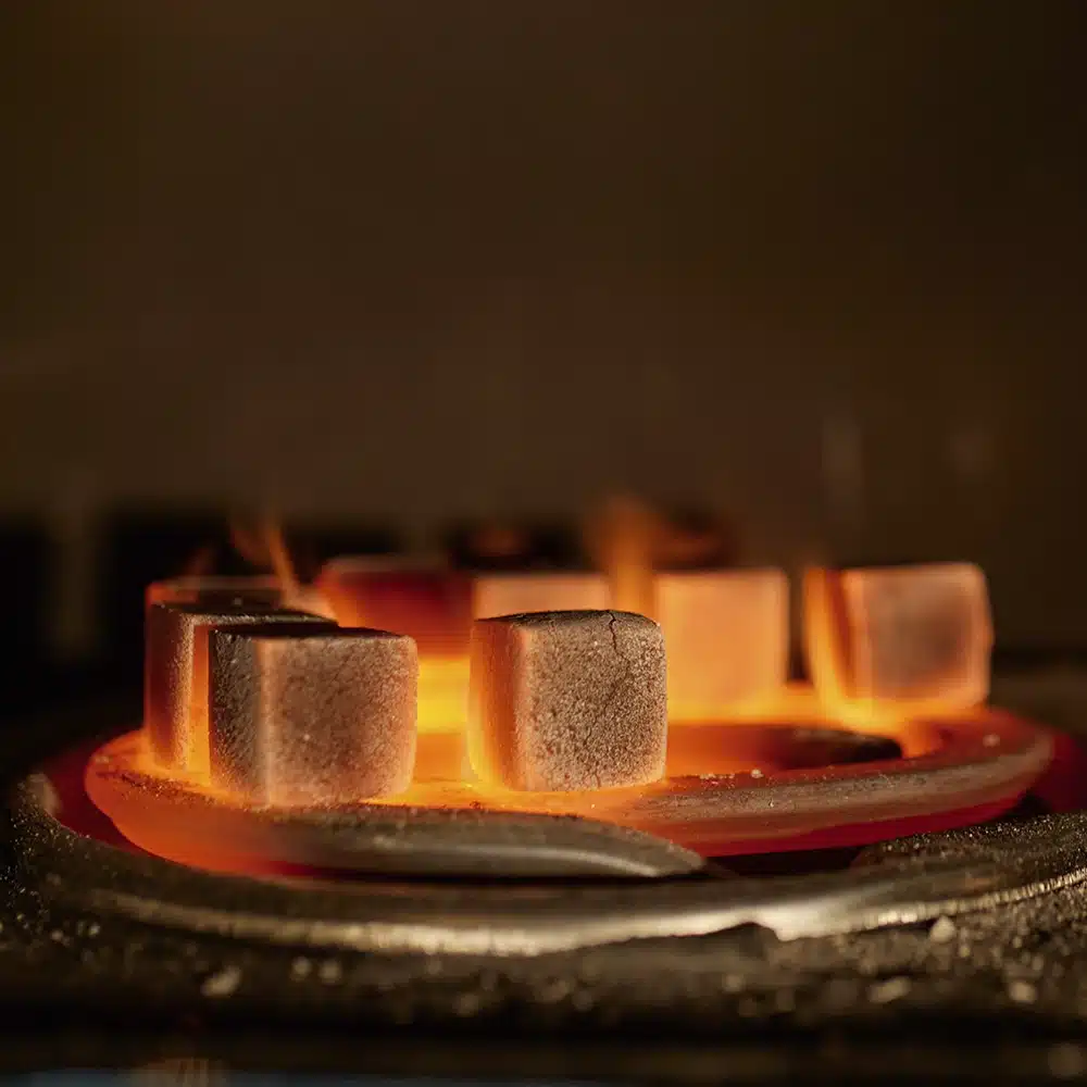 Coconut briquette charcoal glowing orange on a heat source.