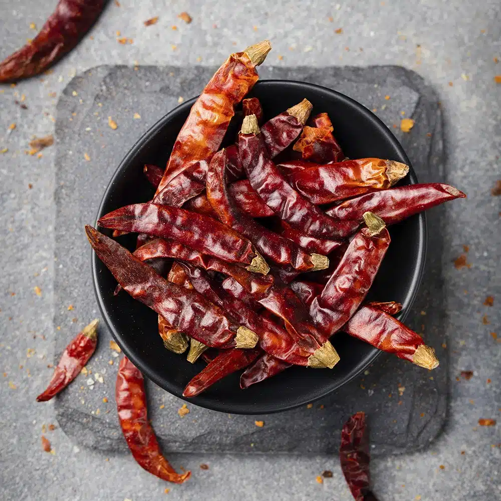 Bowl of dried red chilies on a slate surface.